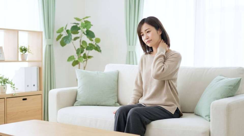 首の後ろに手を当てて様子を確かめる女性(イメージ)