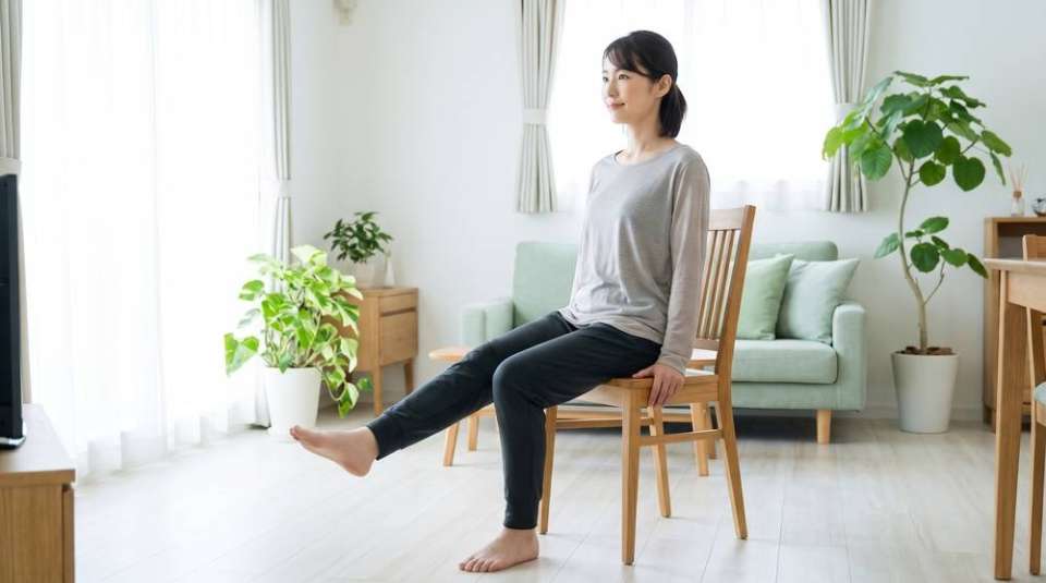 椅子に座って片脚をまっすぐ伸ばす女性(イメージ)